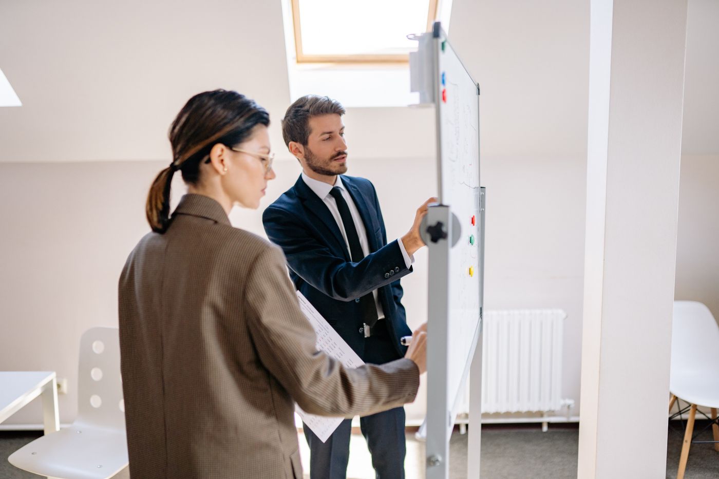 Zwei Personen erarbeiten eine Strategie an einem Whiteboard